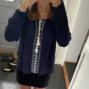 Mörkblå blus med snörning  - Mörkblå blus med vit snörning från Vila i storlek M, passar även S. Fint skick. Använd gärna köp nu!