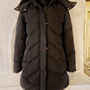 Svart vinterjacka med gulliga detaljer  - Svart vinterjacka med pälsfoder som går att ta bort.