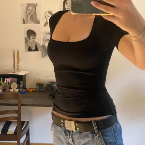 Svart kortärmad topp - Säljer en stilren svart kortärmad topp med en fyrkantig urringning. Perfekt för både vardag och fest. Toppen är i ett mjukt och stretchigt material som sitter snyggt på kroppen.