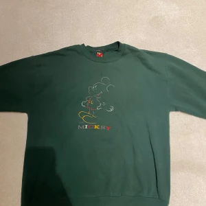 Disney tröja grön - Fin vintage Disney tröja med mickey mouse broderat på framsidan. Äkta vintage och gjord i usa. Den har ca tre fläckar på framsidan. Storlek XL, funkar som en oversized tröja (är 158cm lång). Axelbredd 58cm x längd 70cm  Skicka PM vid köp/fråga🫶