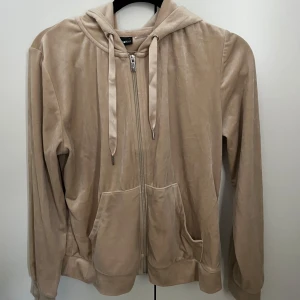 Beige hoodie med dragkedja - Säljer en supermjuk och skön beige hoodie med dragkedja framtill. Den har en avslappnad passform och är perfekt för både höst och vår. Koftan har långa ärmar och en praktisk huva med snören. Fickor framtill för extra mysfaktor. Passar även storlek M.