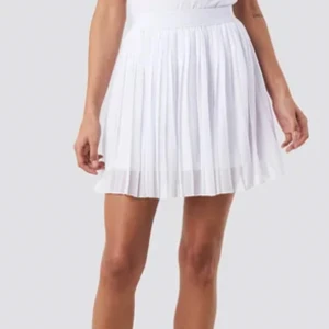 Vit plisserad kjol - Säljer en superfin vit plisserad kjol som är perfekt för sommaren! Den har en elastisk midja som gör den bekväm att bära hela dagen. Kjolen är kort och har en luftig känsla, vilket gör den idealisk för varma dagar eller en somrig fest. Passar perfekt med en enkel topp eller blus.