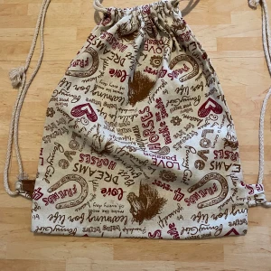 Gympaväska i tyg - Gympaväska av grövre tyg med häst tryck. Den är 39cm hög och 30cm bred. Den har lite lös trådar som man kan se på sista bilden, men det är ej håll och påverkar inte väskan.