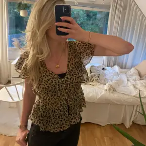 Säljer en superfin leopardmönstrad blus med volangdetaljer. Den har korta ärmar och en luftig passform, perfekt för både vardag och fest. 