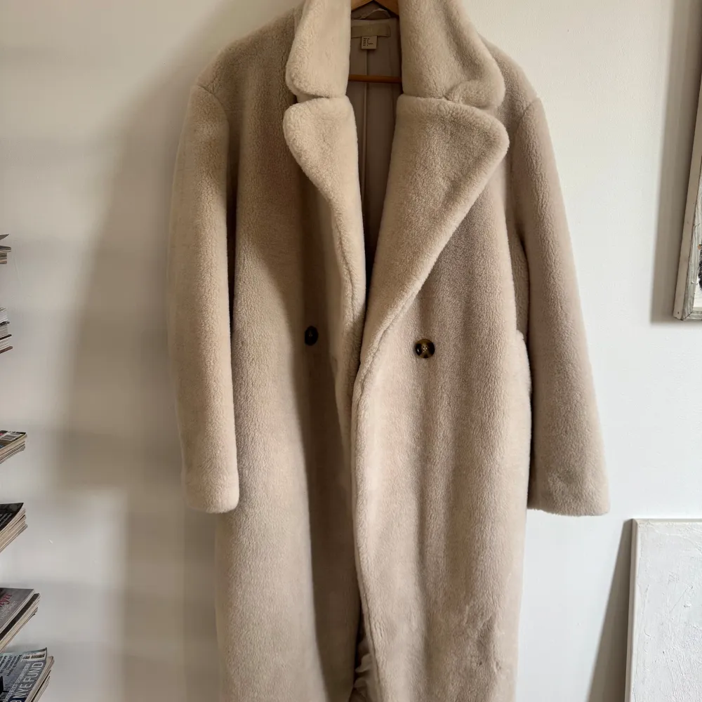 Säljer en supermysig beige teddyjacka /päls från H&M i storlek 40. Den har en klassisk design med stora knappar framtill och långa ärmar. Perfekt för kalla höst- och vinterdagar när du vill hålla dig varm och stilren. Jackan är i nyskick!. Jackor.