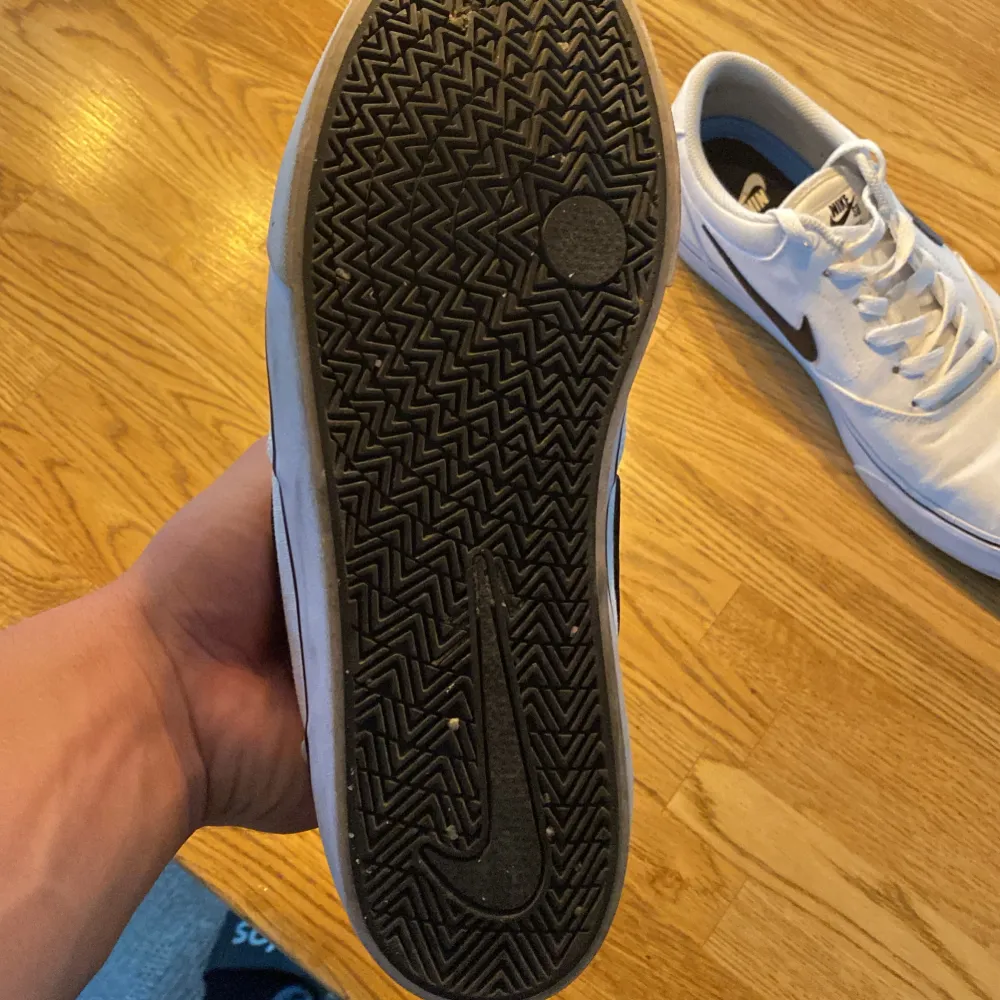 Säljer ett par vita Nike sneakers med den klassiska svarta Swoosh-loggan på sidan. Skorna har snörning och en bekväm passform. De är i välanvänt skick men fortfarande snygga och funktionella. Perfekta för vardagsbruk!. Skor.