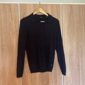 Stickad tröja - Säljer en stilren svart långärmad pikétröja från Only & sons. Perfekt för både vardag och lite mer uppklädda tillfällen. Tröjan har en klassisk krage och knappar framtill. Den är i bra skick och passar perfekt till höst- och vårgarderoben.