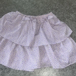 Lila kjol med blommor  - Fint skick.  Aldrig använd 