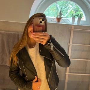 Svart skinnjacka från Vegas - Säljer en snygg svart skinnjacka från Voyelle. Den har en cool bikerstil med dragkedjor och bälte i midjan. Perfekt för höst och vår när du vill ha en edgy look. Jackan är i bra skick och har långa ärmar.