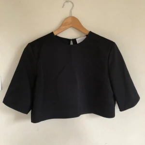 Nathalie Schuterman T-shirt - Axelvaddad svart T-shirt I tjockt satäng tyg från Nathalie Schuterman.  Storlek S.   Köpte den här T-shirten och en kjol med tillhörande top (3 plagg) för att ha på mig på en fest men blev annan utstyrsel när dagen väl kom.  Oanvända med prislapparna