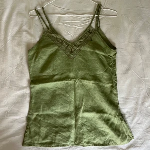 Figursydd topp med brodyr  - Lite sage grön topp med super fin brodyr upp till. Fin passform med dragkedja på ena sidan. Färgen ser ut som i sista bilden. 