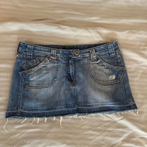 Blå jeanskjol med fransig kant - Säljer en snygg blå jeanskjol med fransig kant och slitna detaljer. Super snygg i fint skick med snygga detaljer!!💓