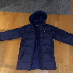 Mörkblå pufferjacka från Lyle & Scott - Säljer en mörkblå pufferjacka från Lyle & Scott med huva och dragkedja. Storleken är 14/15 år men skulle gissa att det är Small. Hör av er vid frågor 
