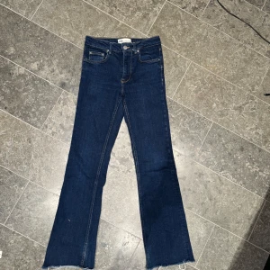 Blå bootcut jeans - Snygga blå bootcut jeans med klassisk femficksdesign och fransade benslut. Perfekta för en avslappnad stil med en touch av retro. De har en dragkedja och knapp framtill. Innerbenslängd 75cm midjemått 34❤️ 