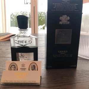 Creed Aventus Parfym 100 ml - Exklusiv Creed Aventus parfym i en elegant glasflaska med svart detaljer och en stilren etikett. Flaskan rymmer 100 ml av denna ikoniska doft, känd för sin unika och kraftfulla karaktär. Förpackningen är lyxig med en svart kartong och silverdetaljer. Skriv innan ni köper 