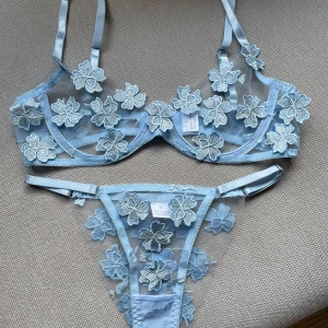 Blå blommig spets-bh och trosa - Jättefint blått lingerieset med blommor. Okänt märke, köpt i boutique utomlands. Helt oanvänt, storlek S med justerbara band på bägge delarna. Bh:n passar A och B kupa