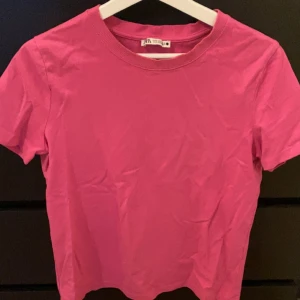 Rosa t-shirt från Zara - Säljer en snygg rosa t-shirt från Zara. Den är kortärmad och tillverkad i ett mjukt bomullsmaterial. Perfekt för en avslappnad stil. Passar bra till jeans eller kjol. 🌸