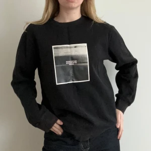 Svart långärmad tröja med tryck - Snygg svart långärmad tröja med ett stilrent tryck på framsidan. Perfekt för en casual look och passar bra till jeans. Tröjan har en normal passform och är gjord i ett mjukt material för extra komfort.