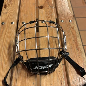 Jofa galler m - Säljer ett robust ansiktsskydd från Jofa, perfekt för hockey. Tillverkat i metall med justerbara remmar för säker passform. Storlek M priset går att diskutera