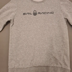 Sail Racing tröja - Jag säljer min gråa sail racing tröja då den inte kommer till användning den är i fint skick. Tröjan är i storlek 170 så det motsvarar storlek XS i vuxenstorlek skriv om ni har några frågor