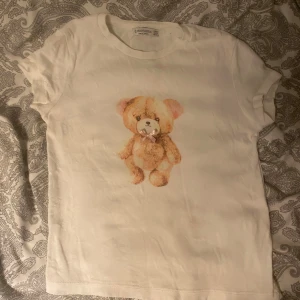 Vit t-shirt med nallemotiv från Stradivarius - Söt vit t-shirt från Stradivarius med nalle på framsidan. använd men det ut som nyskick ☀️skickar inom 24h☀️