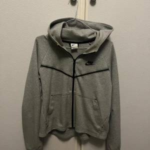 Grått Nike Tech set  - Säljer mitt gråa nike tech set som aldrig kommer till användning:) Köpte setet för något/några år sedan på stadium i USA men jag har bara använt de ett fåtal gånger. Perfekt för en sportig look eller avslappnade dagar. Jag kan tvätta de innan det säljs så att de lilla smink fläckarna som finns vid kragen försvinner!:) Annars är de i princip i nyskick! Nypris: ca 2000kr