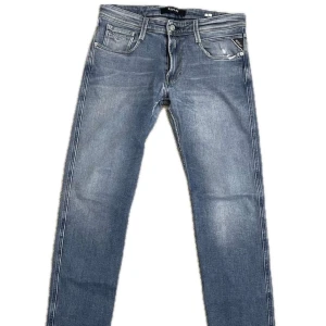 Blå jeans från Replay - Snygga blå jeans från Replay med klassisk femficksdesign och knappgylf. De har en stilren look med lätt slitna detaljer och en bekväm passform. Perfekta för en avslappnad stil. Storlek W31 och L32