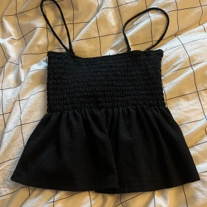Svart somrig topp från Gina Tricot - Säljer en svart topp från Gina Tricot med tunna axelband. Toppen har en luftig och bekväm passform. Perfekt för varma dagar eller som ett lager under en jacka. Axelbanden går att ta av och man kan även ha den som en kjol, nyskick har använts 2 gånger 💞