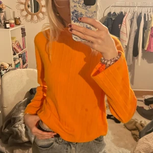 Orange ribbad tröja - Säljer en cool orange ribbad tröja med långa ärmar. Perfekt för att lysa upp garderoben med en pop av färg. Tröjan har en bekväm passform och är lätt att matcha med jeans eller kjol.