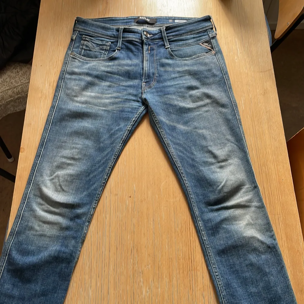 Säljer ett par snygga blå jeans från Replay i modellen Anbass. De har en klassisk femficksdesign med en cool tvätt som ger dem en avslappnad look. Jeansen är i bra skick och perfekta för både vardag och fest. Passformen är slim och de har en dragkedja i gylfen.. Jeans & Byxor.