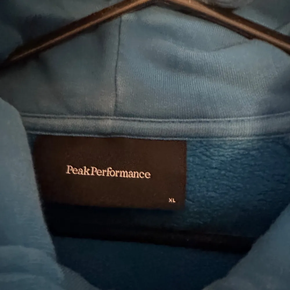 Säljer en snygg blå hoodie från Peak Performance i storlek XL. Den har en dragkedja framtill och en skön huva. Perfekt för kyliga dagar eller som ett extra lager. Den är i bra skick och redo för nya äventyr! 💙. Neuletakit & Villapaidat.