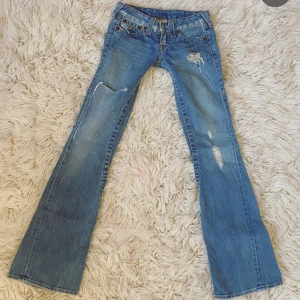 Ljusblå true religon bootcut jeans med slitningar - Midja: ca 70-72 cm runt hela (35-36 cm rakt över)💕 Innerben: ca 83 cm⭐️ Grenhöjd: Ca 16 cm⭐️ De helt perfekta superlågmidjade jeansen från true religon som tyvärr är för små för mig😭😭 Försöker posta samma dag eller dagen efter💕 Tryck gärna på köp nu!!💕