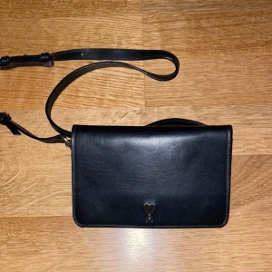 AMI PARIS väska - Säljer denna ami väska i svart med axelband. Mycket fint skick och nästan helt oanvänd.