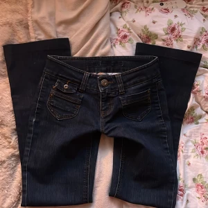 Mörkblå lågmidjade jeans från Only - Säljer ett par snygga mörkblå jeans från Only. De har en klassisk femficksdesign med knappar och dragkedja fram.  Tvärsöver midjan är det 37 cm och innerbensmåttet är ca 75 cm💖