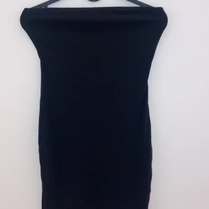 Svart axelbandslös klänning - Snygg svart axelbandslös klänning i tight passform. Perfekt för festliga tillfällen eller en utekväll. Enkel och stilren design som framhäver figuren.