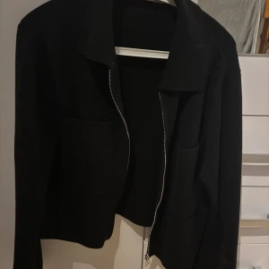 Svart jacka från Åhléns - Säljer en stilren svart jacka från Åhléns i storlek S. Jackan har en dragkedja framtill och är perfekt för både vardag och fest. Den är i mycket bra skick och passar till de flesta outfits. Perfekt för höst och vår!