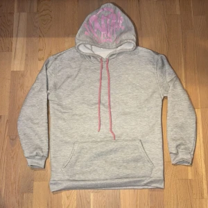 Synaworld set - Säljer ett set med en grå hoodie och matchande byxor. Hoodien har en cool rosa text på insidan av huvan och rosa snören. Byxorna har samma rosa text på baksidan. Setet är i bra skick och superbekvämt!