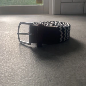 Snyggt flätat bälte med bruna detaljer - Säljer ett stilrent flätat bälte i svart och vitt med snygga bruna skinn-detaljer. Perfekt för att piffa upp vilken outfit som helst! Bältet har ett silverfärgat spänne som ger en modern touch. Passar både till vardags och fest. 🖤🤍