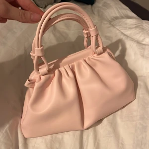 Ljusrosa handväska - Säljer en superfin ljusrosa handväska i syntetmaterial. Den har en mjuk och rynkad design med dubbla handtag som ger en söt och elegant look. Perfekt för både vardag och fest! 💖Som nytt 