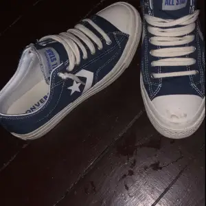 Säljer ett par klassiska blå Converse sneakers i bra skick. De har den ikoniska stjärnloggan på sidan och vita snören. Perfekta för vardagsbruk och ger en avslappnad stil. Passar till både jeans och shorts!