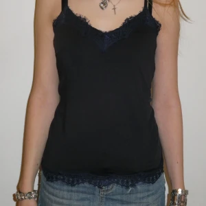 Mörkblått linne med spetsdetaljer - Snyggt mörkblått linne med spetsdetaljer upptill och nertill. 