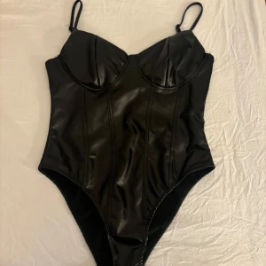 Svart läder body från Shein - Snygg svart läder body från Shein i mycket bra skick. Den har justerbara axelband, och är i storlek M. Har aldrig använt den tidigare då den inte passade. 