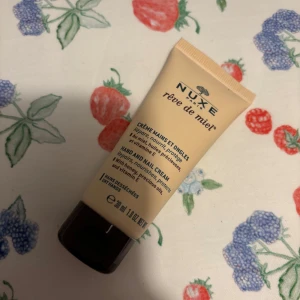 Nuxe Rêve de Miel Hand and Nail Cream - En lyxig hand- och nagelkräm från Nuxe, perfekt för torra händer. Den innehåller honung och värdefulla oljor som ger näring och skydd. Tuben är smidig och lätt att ta med sig, perfekt för väskan. Doftar underbart och absorberas snabbt utan att kladda.