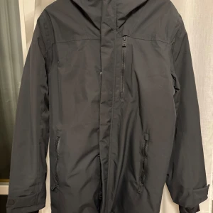 Svart parkajacka med dragkedja - Säljer en stilren svart parkajacka i mycket bra skick. Jackan har långa ärmar och flera praktiska dragkedjor, perfekt för höst och vinter. Den är både funktionell och snygg, idealisk för kyligare dagar. Passar bra till både vardag och lite finare tillfällen.