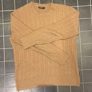 Beige stickad tröja från Tiger of Sweden - Säljer en snygg beige stickad tröja från Tiger of Sweden i storlek M. Tröjan har ett klassiskt kabelstickat mönster och är perfekt för både höst och vinter. Tröjan består av hel 80% bomull och kommer hålla dig varm under vintern. Den är dyr i vanliga fall men säljer den till ett lågt pris på grund av att jag vill bli av med nu då den inte kommer tilll användning. Den är ett mycket bra skick men lite nopprig dock inget man tänker på!