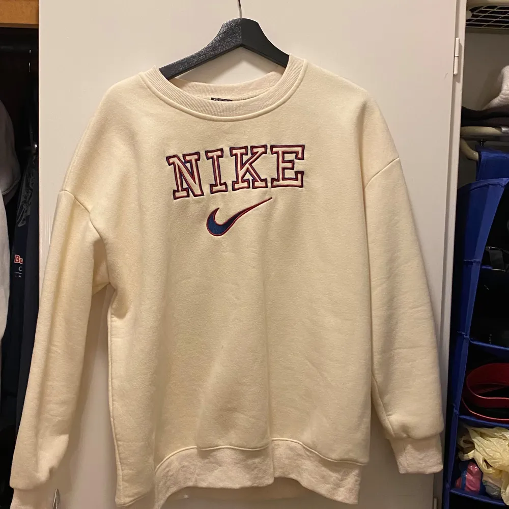 Säljer en superbekväm beige sweatshirt från Nike i storlek XL. Den har ett stort Nike-logotyptryck i rött och blått på framsidan. Perfekt för en avslappnad stil och passar till alla årstider. Tröjan är i mycket bra skick och redo för nya äventyr!. Tröjor & Koftor.