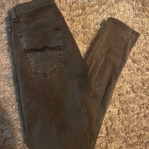 Mörkgråa Nudie Jeans - Säljer ett par mörkgråa nudie jeans i skin fit, som är väldigt trendiga just nu✨. De är i nyskick, och storlek W31 L32 . Hör av dig vid frågor✅