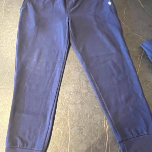Mörkblå mjukisbyxor från Polo Ralph Lauren - Säljer ett par mörkblå mjukisbyxor från Polo Ralph Lauren i storlek XL (Funkar perfekt som L) Byxorna är i mycket bra skick och har en bekväm passform med elastisk midja. Perfekta för en avslappnad dag hemma eller en promenad i parken. 🏠💙
