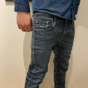 Jacob Cohën jeans - Säljer ett par snygga blå jeans från Jacob Cohën i bra skick. De har en klassisk femficksdesign med knappgylf och märkeslogga på insidan av midjan. Jeansen har en slim passform. De är tillverkade i högkvalitativt denim. De har en liten skada på vänstra knät men annars väldigt bra skick. Säljer då de inte kommer till användning och har blivit för små! 