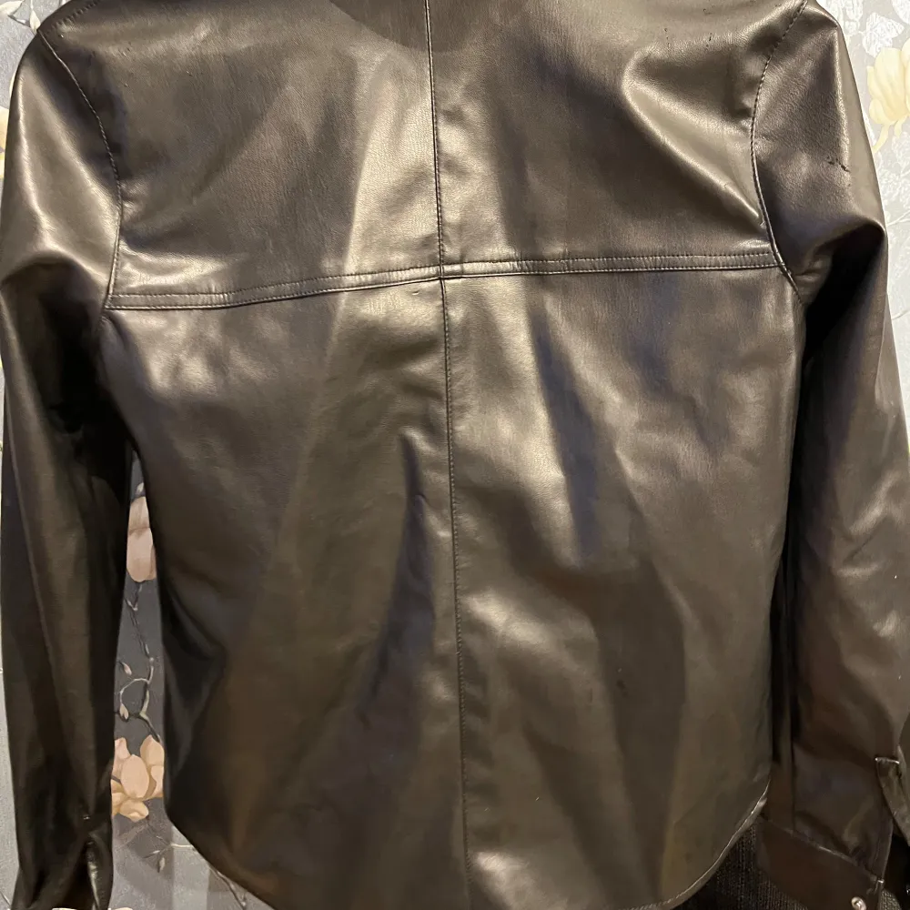 Snygg svart skinskjorta i mycket bra skick. Den har en klassisk krage och knappar framtill. Perfekt till fest som till vardags. Skjortan har långa ärmar och en stilren design.. Paidat.
